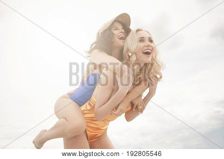 Two beautiful girls in bikinis laughing and having fun on the beach