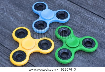 Three fidget spinner stress relieving toy on a wooden background.