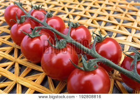 Fresh cherry tomatoes on a background of a straw mat.