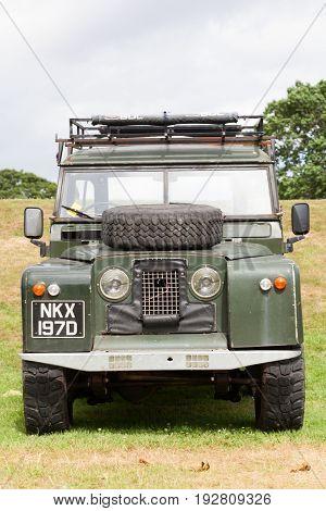 BEAULIEU HAMPSHIRE UNITED KINGDOM - JUNE 25 2017 Land Rover day with many varieties of Land Rovers including this Land Rover Series 2 in a green color parked on the grass on a cloudy day.