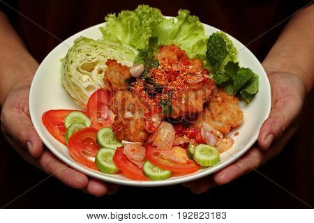 Thai food Spicy crispy deep-fried chicken salad call Yum Kai Zap in Thai topped cucumber green oakcabbage and tomato.