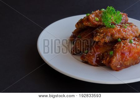 Barbecue chicken wings on white plate served with barbecue dipping sauce. Homemade bbq chicken wing delicious, moist and spicy. Barbecue chicken wing ready to served on granite table with copy space for background or wallpaper.