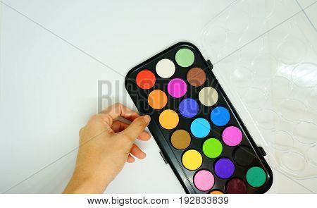 Hand holds colorful Eyeshadow, Watercolors Palette Isolated on White Background