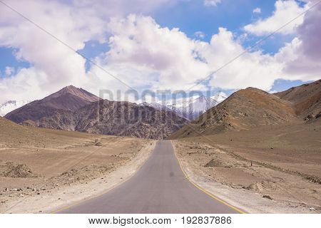 Scenic view from the asphalt road in to the mountains  and the desert
on the side of  road. Blue sky and clouds