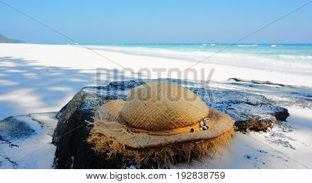 Hat placed on  rock. Sand beach and blue sky background.