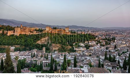Wide view of Granada and the ancient arabic fortress of Alhambra at dusk with Sierra Nevada in the background. Spain.