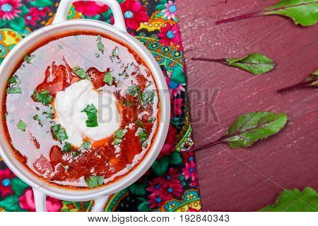 Ukrainian traditional borsch. Russian vegetarian red soup  in white bowl on red wooden background. Top view.  Borscht, borshch with beet