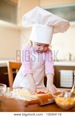 Bambina taglia pasta per biscotti in cucina con la forma