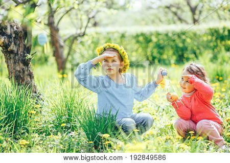Two girls of Asian and Caucasian appearance collect Easter eggs in the lush garden
