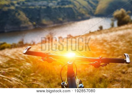 Moutnain bike handlebar against summer landscape. Mountains and river on background. Weekend journey on bicycle. Outdoor recreation. Active life concept.