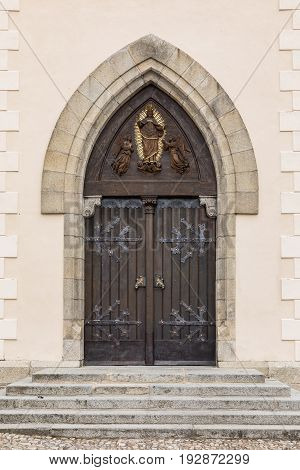 Old wooden oak arched gothic church doorway with black wrought iron hinges. Large wooden door with wrought-iron elements. Decorative door with fittings.