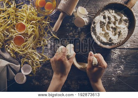 Woman cook hands preparing making tasty homemade classic italian pasta on wooden table. Closeup. Top View. Toning.