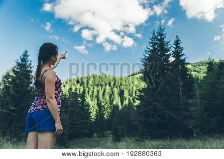 Woman tourist point on something in forest inCarpathian mountains