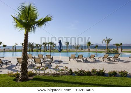 Recliners sul patio di piscina resort guardando verso il mare