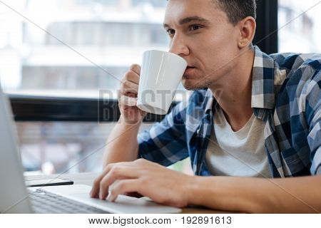 Take a sip. Hardworking industrious quick witted man having productive time while spending some time in the cafe and reading his mail