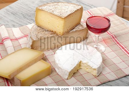 Different french cheeses with a glass of red wine