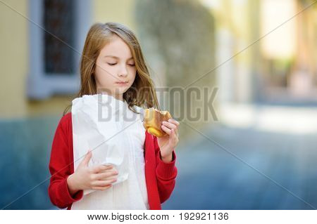 Adorable Little Girl Eating Fresh Baked Bun On Warm And Sunny Summer Day In Toscolano-maderno Town