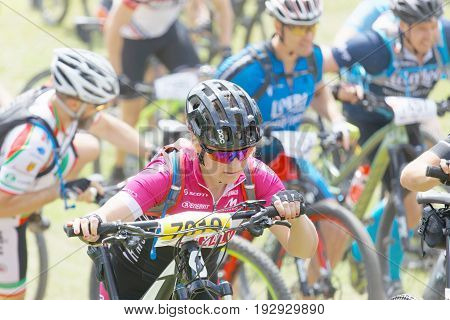 STOCKHOLM SWEDEN - JUNE 11 2017: Woman leading her mountain bike uphill at Lida Loop Mountain bike Race audience in background. June 11 2017 in Stockholm Sweden