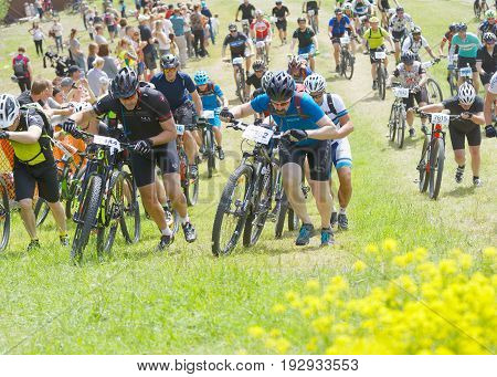 STOCKHOLM SWEDEN - JUNE 11 2017: Group of men leading his mountain bike uphill competitors behind at Lida Loop Mountain bike Race audience in background. June 11 2017 in Stockholm Sweden