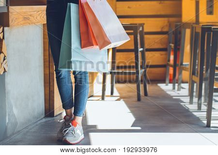 Young female standing in a cafe indoors rest holding shopping bags