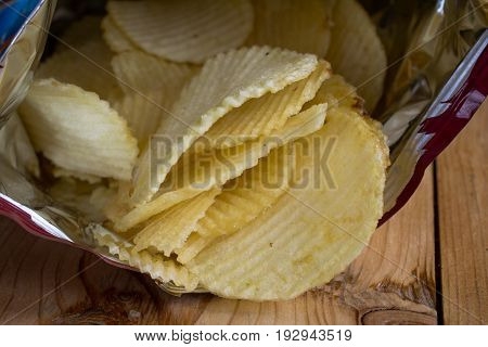 Yellow salted potato chips on wood table