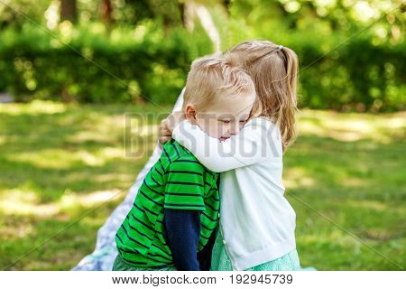 Children hug in the garden. 2-3 years. Girl and boy. The concept is childhood and family.