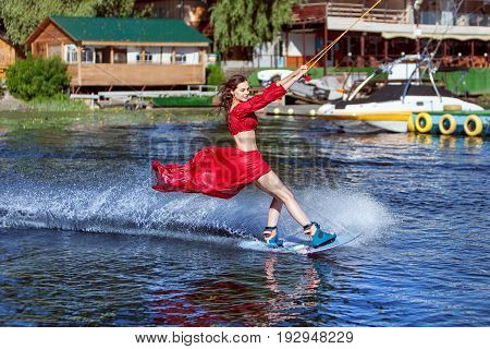 Woman enjoys skating on the lake on a wakeboard.