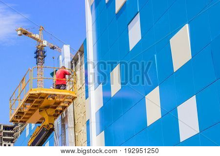 A worker installs panels facing on the facade of the house