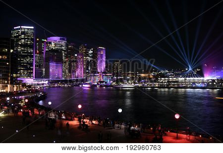 City lights and laser show in Circular Quay during the Sydney Vivid show the free annual outdoor event of light music and ideas. View from Sydney Opera House.