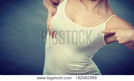 Health care bosom concept. Young woman wearing tshirt holding hands on breast and pushing them up