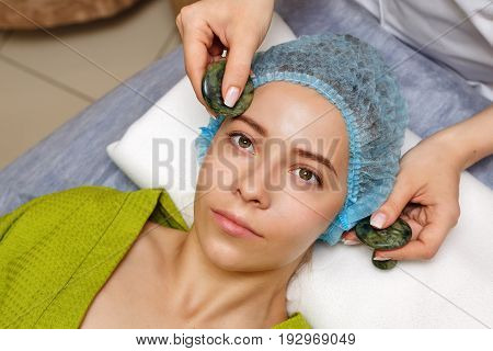 Spa treatment. Face massage with jade stones. Alternative medicine. Massage of forehead zone. Guasha