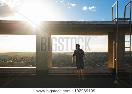 A lonely roofer on the roof of the high-rise at sunset. Courage and adrenaline. Loneliness and calmness