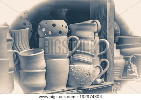 Bright pottery. Many white, not painted clay pottery standing on wooden shelves