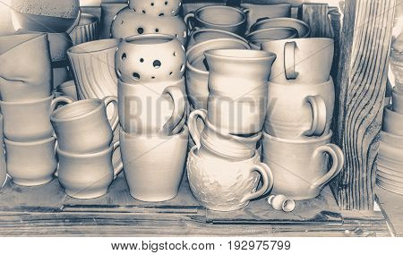Bright pottery. Many white, not painted clay pottery standing on wooden shelves
