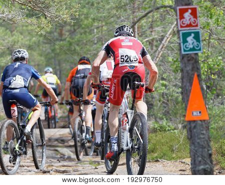STOCKHOLM SWEDEN - JUNE 11 2017: Rear view of group of mountain bike cyclists in the forest at Lida Loop Mountain bike Race. June 11 2017 in Stockholm Sweden