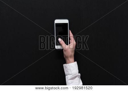 Hand Of Woman Holding Smartphone With Blank Screen Isolated On Black
