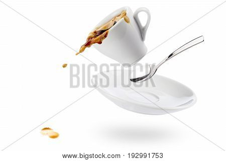 cup of coffee spils with saucer and spoon and coffee falls on white background