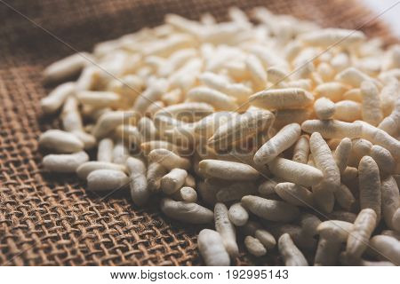 Puffed rice also known as Murmura or Murmure in hindi served in a colourful ceramic bowl or plate or over gunny bag, isolated, selective focus