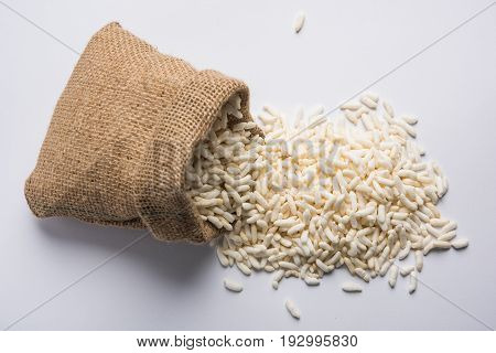 Puffed rice also known as Murmura or Murmure in hindi served in a colourful ceramic bowl or plate or over gunny bag, isolated, selective focus