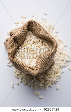 Puffed rice also known as Murmura or Murmure in hindi served in a colourful ceramic bowl or plate or over gunny bag, isolated, selective focus