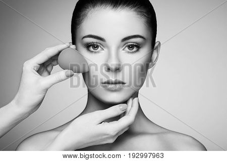 Makeup artist applies skintone. Beautiful woman face. Perfect makeup. Skincare foundation. Sponge makeup artist. Black and White photo
