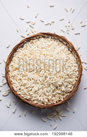 Puffed rice also known as Murmura or Murmure in hindi served in a colourful ceramic bowl or plate or over gunny bag, isolated, selective focus