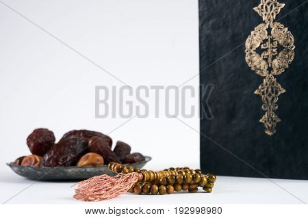 Islamic Holy Book Quran/ Kuran With wooden prayer beads Rosary and dry Dates Over white Background with copy space
