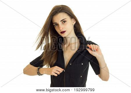 Portrait of a beautiful young girl with hair by air which unzips her jacket and looks into the camera, isolated