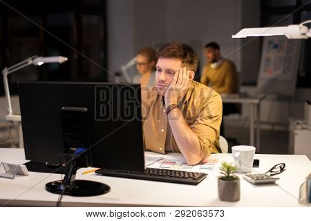 business, overwork, deadline and people concept - tired or bored man working at computer at night office