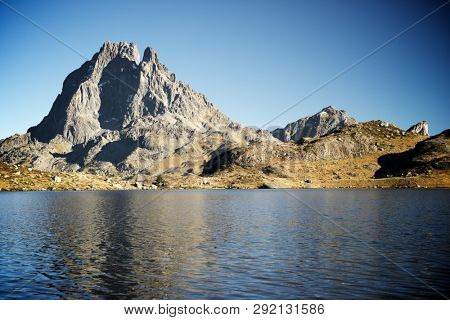 Midi Dossau Peak reflected in Gentau lake. Ossau Valley, Pyrenees National Park, Pyrenees, France.