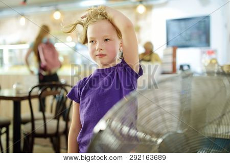 Cute Little Girl Standing In Front Of A Fan On Hot Summer Day. Child Enjoying Cool Wind In Summer Se