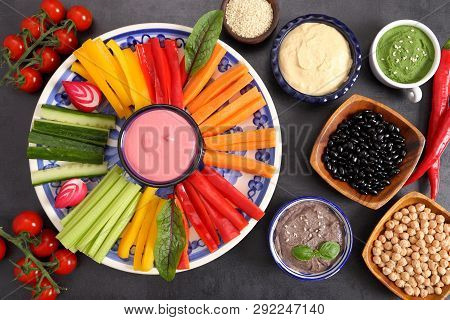 Colorful Fresh Vegetables Cut Into Strips On A Plate And Various Types Of Humus.