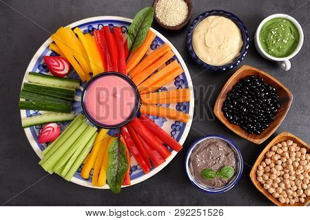 Colorful Fresh Vegetables Cut Into Strips On A Plate And Various Types Of Humus.