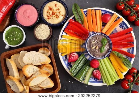Colorful Fresh Vegetables Cut Into Strips On A Plate And Various Types Of Humus.